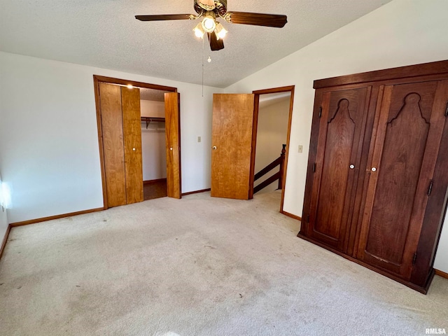 unfurnished bedroom with lofted ceiling, a ceiling fan, light carpet, a textured ceiling, and baseboards