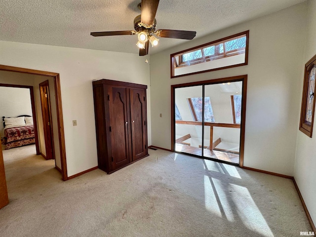 unfurnished bedroom featuring baseboards, a textured ceiling, and light colored carpet