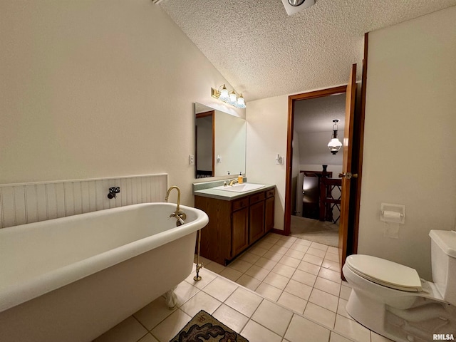 bathroom with a textured ceiling, tile patterned flooring, vanity, a freestanding bath, and vaulted ceiling