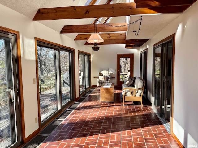 sunroom / solarium featuring lofted ceiling with beams