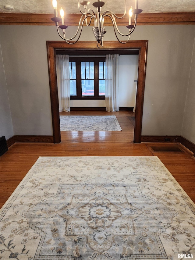 unfurnished dining area with a chandelier, hardwood / wood-style flooring, and ornamental molding