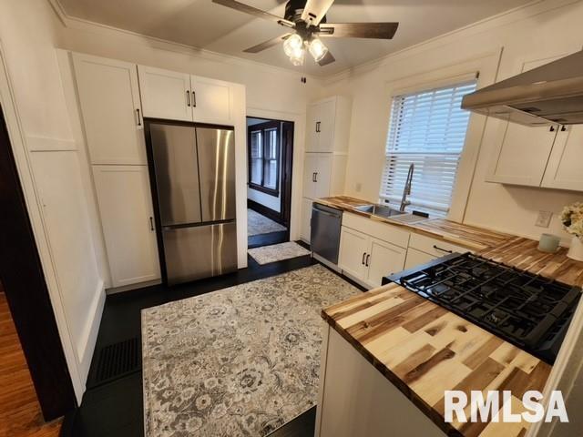 kitchen featuring wood counters, stainless steel fridge, black dishwasher, and white cabinetry