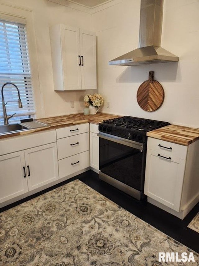 kitchen featuring gas stove, white cabinetry, sink, wall chimney exhaust hood, and crown molding