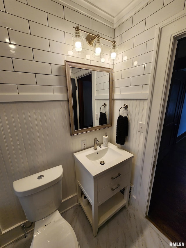 bathroom with vanity, toilet, ornamental molding, and wooden walls