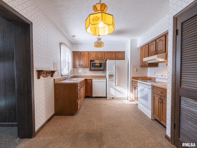 kitchen featuring white appliances, sink, hanging light fixtures, a textured ceiling, and light colored carpet