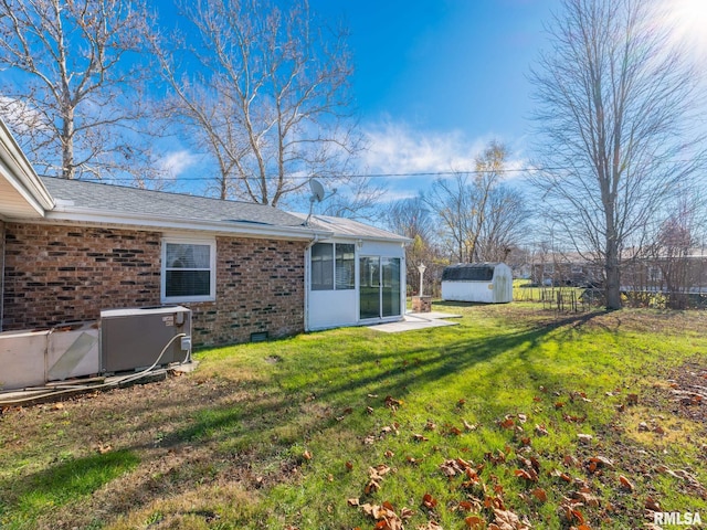 rear view of house with a lawn, a sunroom, and a storage unit