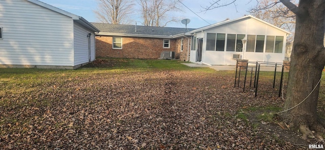 rear view of house featuring a lawn, central AC, and a sunroom