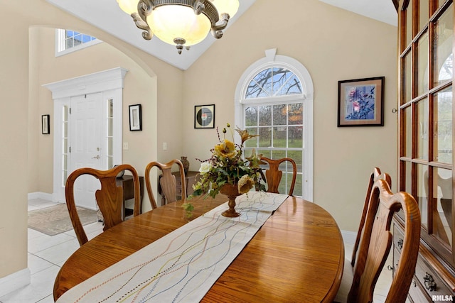 dining space with light tile patterned flooring, lofted ceiling, a wealth of natural light, and a chandelier