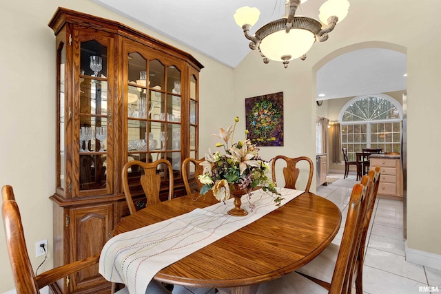 tiled dining room with a chandelier and vaulted ceiling