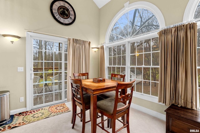 dining room with light colored carpet, plenty of natural light, and lofted ceiling