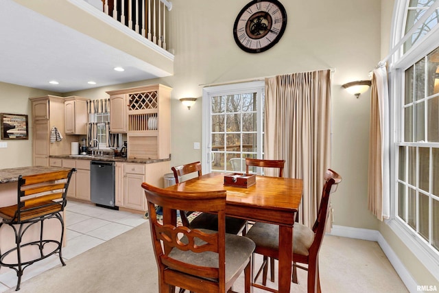 dining room with sink, light carpet, and a high ceiling