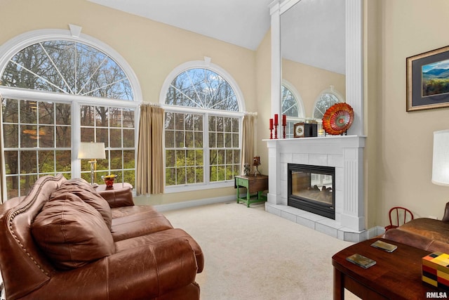 carpeted living room with a tiled fireplace and high vaulted ceiling