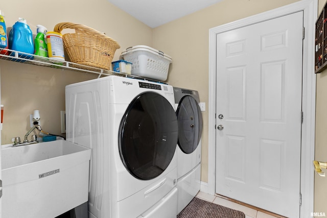 washroom featuring washer and dryer, light tile patterned flooring, and sink