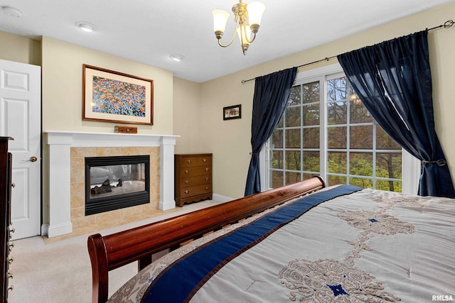 bedroom featuring a tile fireplace, light carpet, and an inviting chandelier