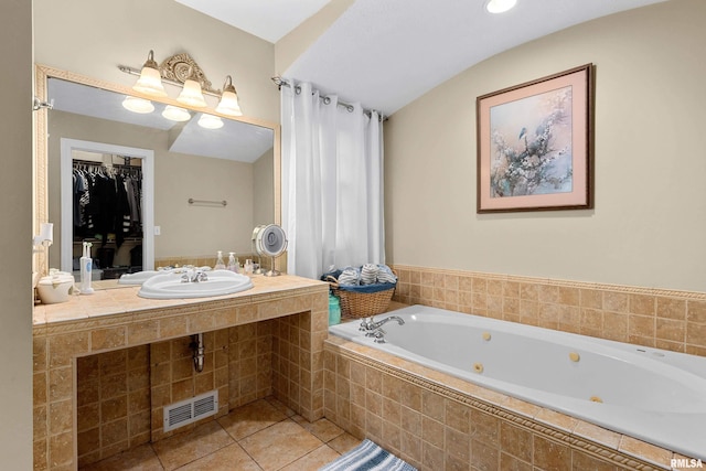 bathroom featuring a relaxing tiled tub, tile patterned floors, and sink