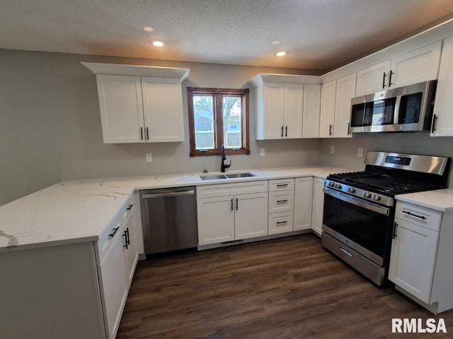 kitchen with light stone counters, stainless steel appliances, sink, white cabinets, and dark hardwood / wood-style floors