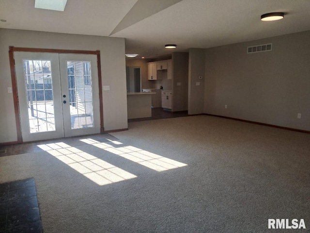 unfurnished living room featuring light carpet, french doors, and lofted ceiling