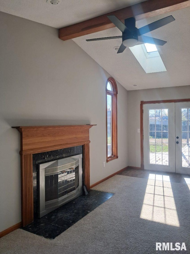 unfurnished living room with carpet flooring, french doors, a textured ceiling, and vaulted ceiling with skylight