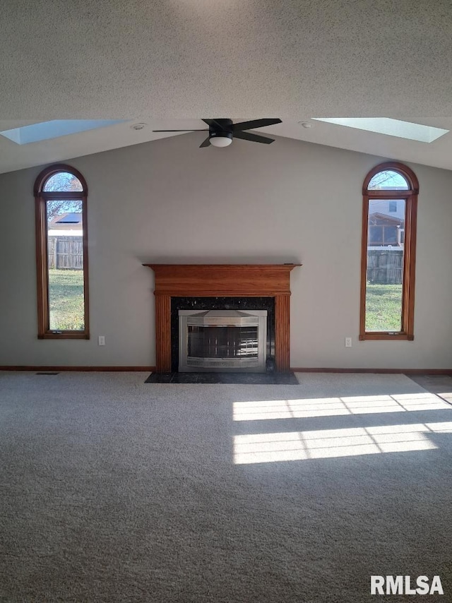 unfurnished living room featuring a textured ceiling, lofted ceiling with skylight, ceiling fan, and a healthy amount of sunlight