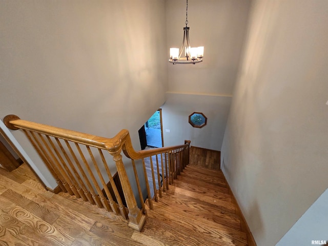 stairway with hardwood / wood-style flooring and an inviting chandelier