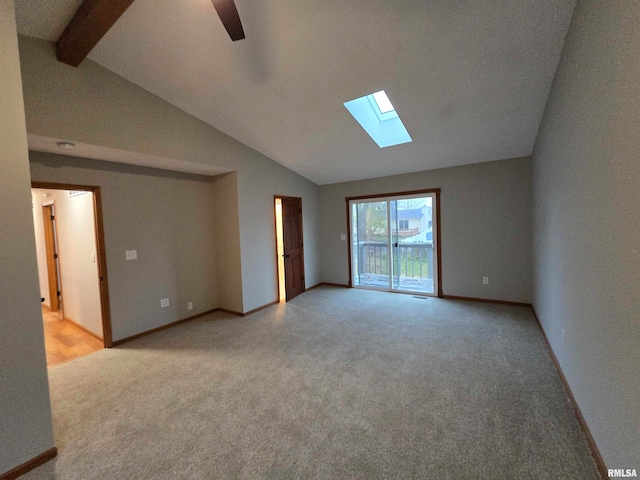 empty room with light colored carpet, ceiling fan, and vaulted ceiling with skylight