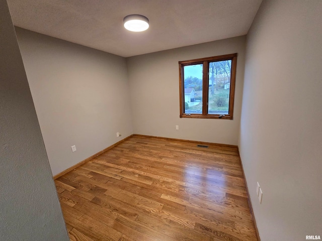 spare room with light wood-type flooring and a textured ceiling