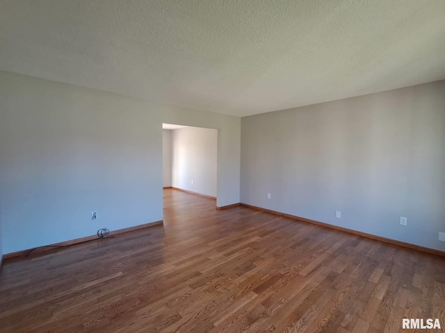 spare room with a textured ceiling and dark wood-type flooring