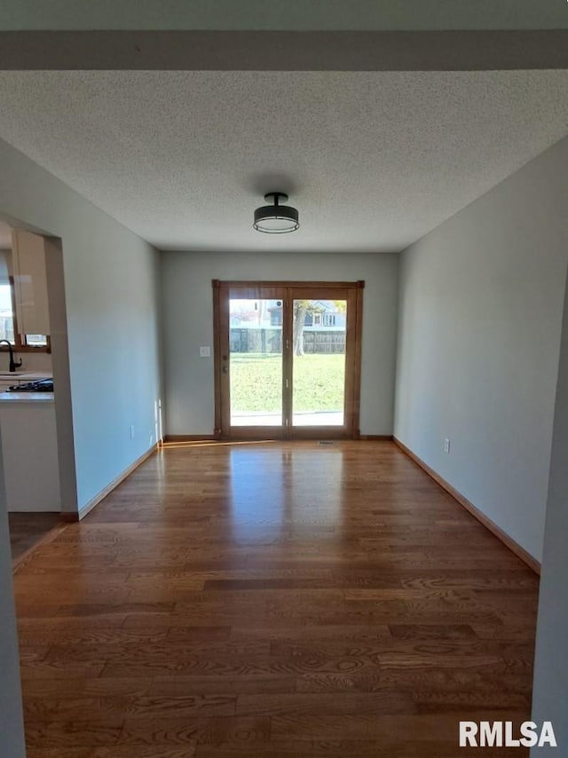 unfurnished room featuring dark wood-type flooring and a textured ceiling