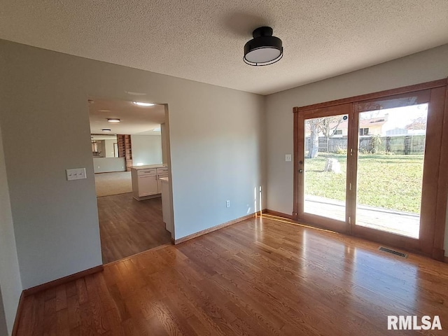 empty room with dark hardwood / wood-style flooring and a textured ceiling