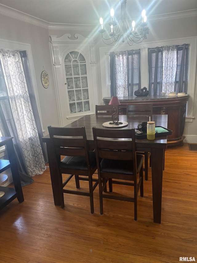 dining room with a chandelier, ornamental molding, and hardwood / wood-style flooring