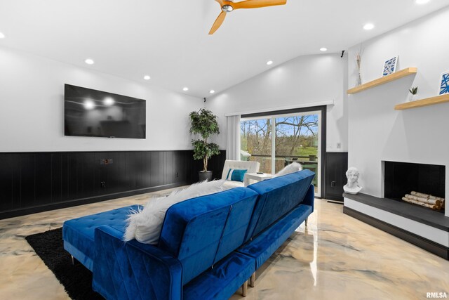 living room with recessed lighting, wainscoting, a fireplace with raised hearth, and vaulted ceiling