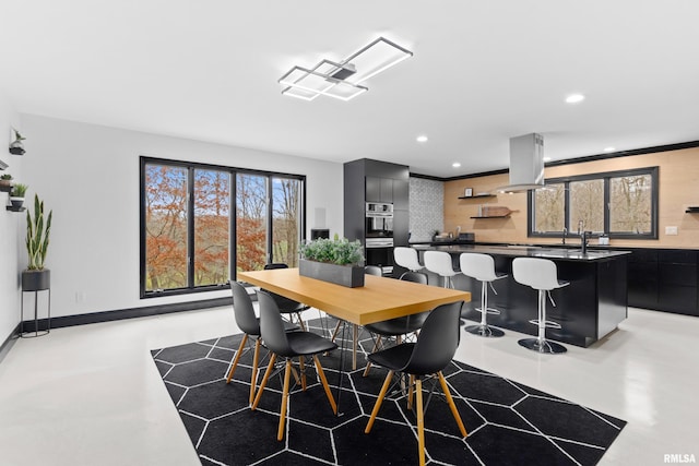 dining area with finished concrete flooring, baseboards, and recessed lighting