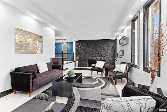 living room with recessed lighting, a stone fireplace, and baseboards