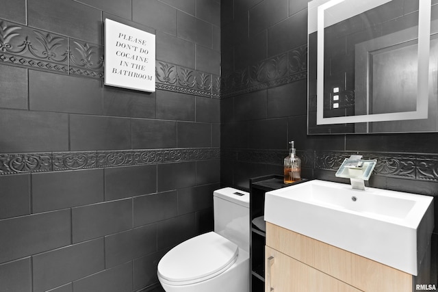 half bath featuring toilet, tile walls, and vanity