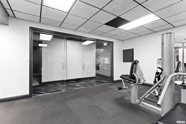 gym with electric panel, baseboards, and a drop ceiling