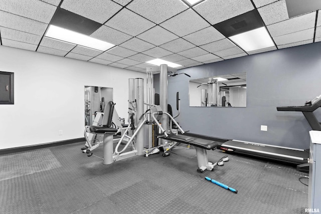 exercise room featuring a drop ceiling and baseboards