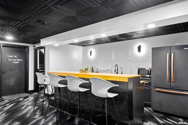 bar featuring an ornate ceiling, appliances with stainless steel finishes, dark wood-style flooring, indoor wet bar, and recessed lighting