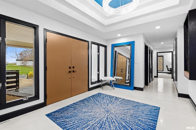 entrance foyer with recessed lighting, a raised ceiling, finished concrete flooring, and baseboards