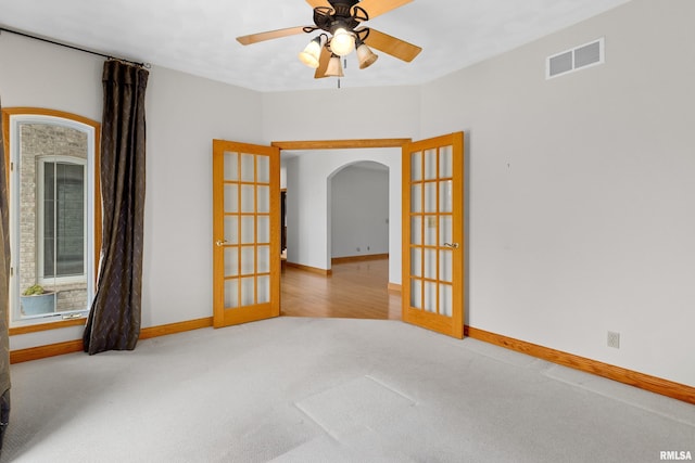 carpeted spare room featuring ceiling fan and french doors