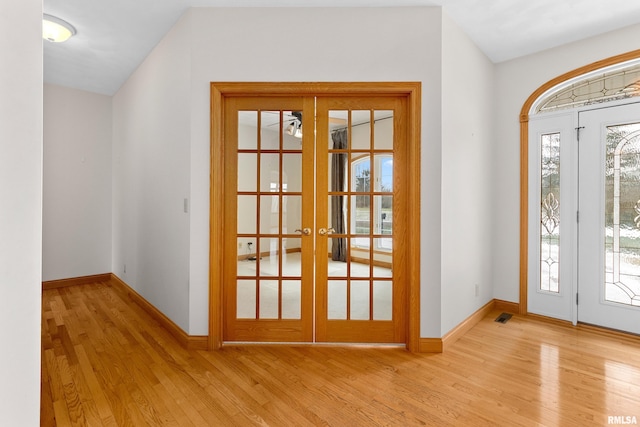 doorway to outside with french doors, vaulted ceiling, and light hardwood / wood-style flooring