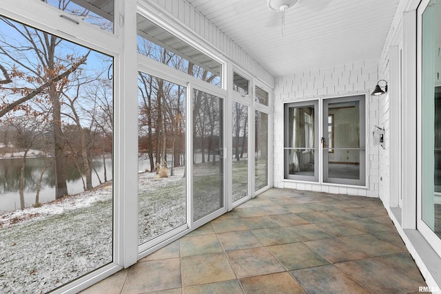 unfurnished sunroom featuring a water view, ceiling fan, and a healthy amount of sunlight