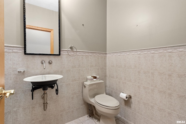 bathroom featuring tile patterned flooring, toilet, and tile walls