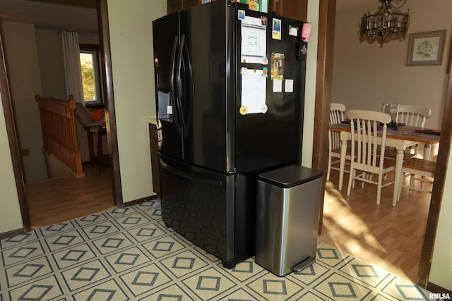 kitchen with a chandelier, light wood-type flooring, and black refrigerator with ice dispenser