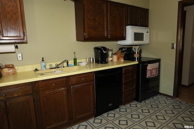 kitchen featuring black appliances, dark brown cabinetry, and sink