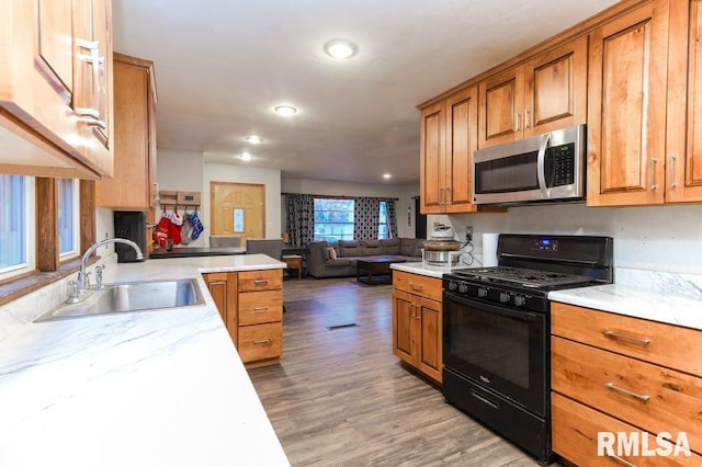 kitchen with black gas stove, hardwood / wood-style floors, and sink