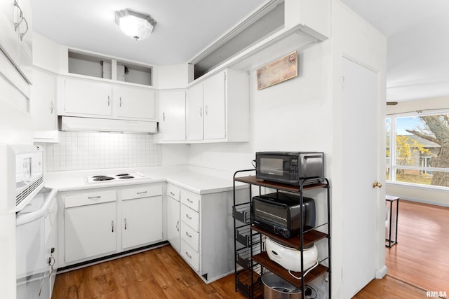 kitchen featuring tasteful backsplash, light hardwood / wood-style flooring, white cabinets, and white stovetop