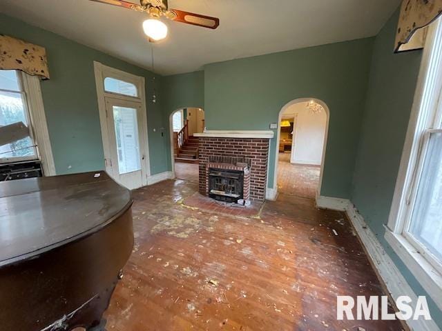 unfurnished living room with ceiling fan and a brick fireplace