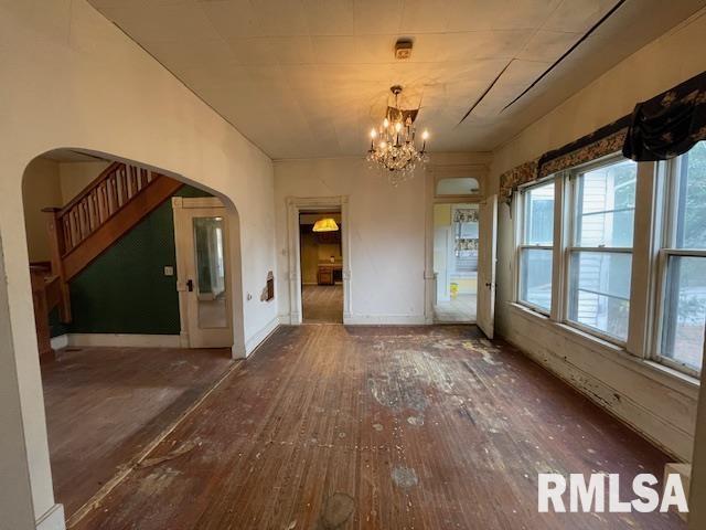 704 S Lafayette St, Macomb, IL 61455 - unfurnished dining area with arched walkways, hardwood / wood-style floors, a chandelier, and plenty of natural light