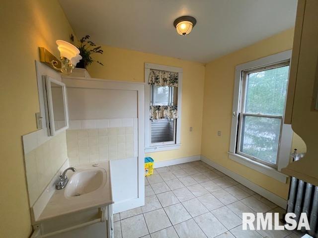 704 S Lafayette St, Macomb, IL 61455 - bathroom with vanity, healthy amount of natural light, tile patterned flooring, and radiator