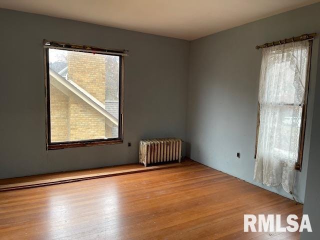 empty room featuring radiator heating unit and light hardwood / wood-style floors